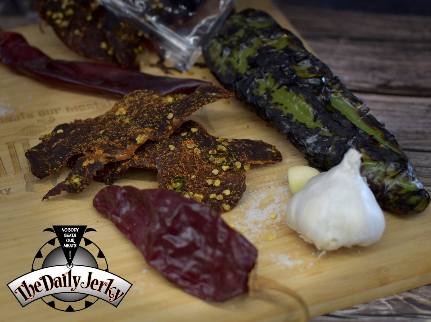 Close up of Christmas beef jerky pieces from The Daily Jerky with  roasted green Chile and dried red Chile pods 