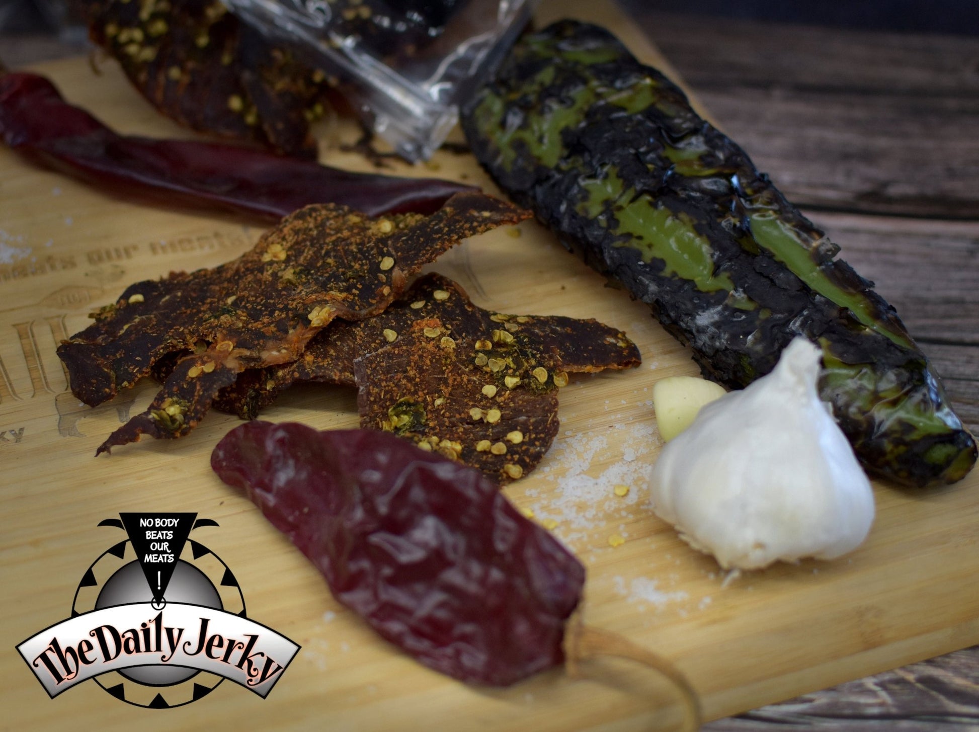 Close up of Christmas beef jerky pieces from The Daily Jerky with  roasted green Chile and dried red Chile pods 