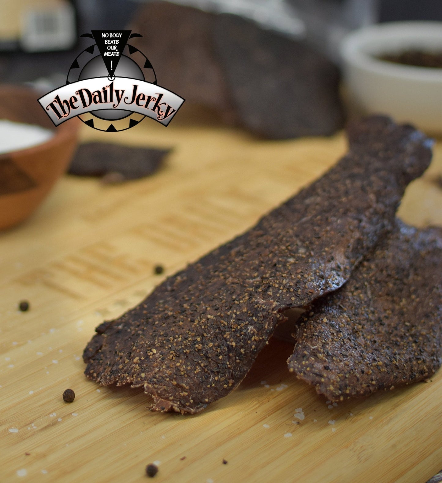 Salt and pepper beef jerky from The Daily Jerky served on a wooden board as a clean high protein snack