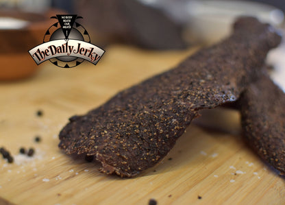Close up of salt and pepper beef jerky pieces from The Daily Jerky with visible black pepper